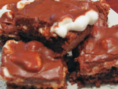 closeup image of slices of rich chocolatey mississippi mud cake with fudge brownies topped with melted marshmallows, pecans and thick chocolate fudge frosting