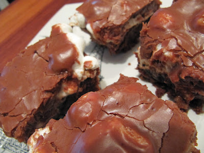 several squares of mississippi mud cake chocolate dessert with a brownie layer, melted marshmallows, pecans, and fudge frosting.