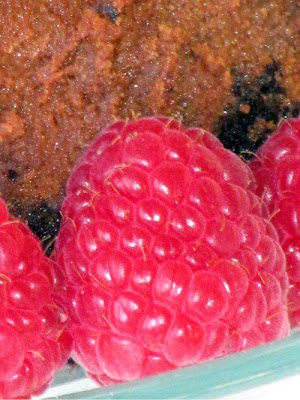 Close-up of rich chocolate cheesecake with fresh raspberries.