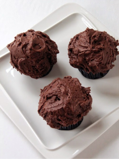 top view of three chocolate cupcakes with creamy chocolate buttercream frosting.