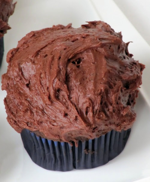 closeup top view of a chocolate cupcake  frosted with a layer of thick creamy chocolate buttercream .