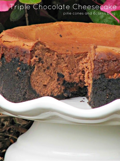 triple chocolate cheesecake with an oreo crust on a white cake stand.