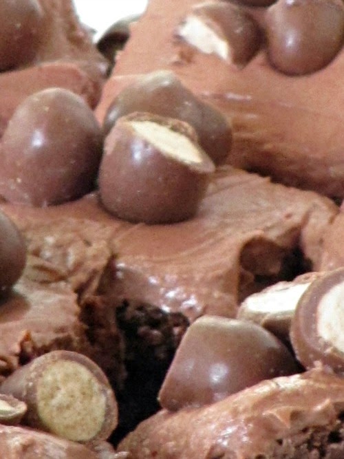 Closeup of some Whopper Brownies with Chocolate Malt Buttercream Frosting and chopped chocolate malt ball candies on top.