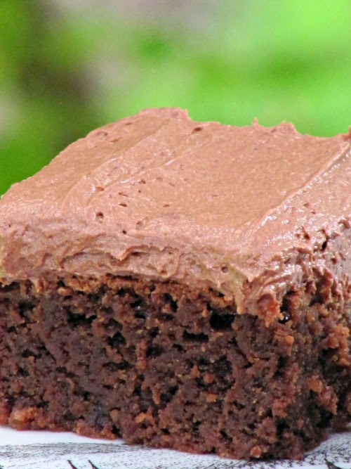 closeup angled view of a Joy the Baker Chocolate Frosted Brownie against a green background.