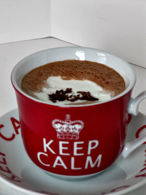 closeup of gingerbread hot cocoa in a large red mug that says "Keep Calm" on a white and red saucer on a white table. 
