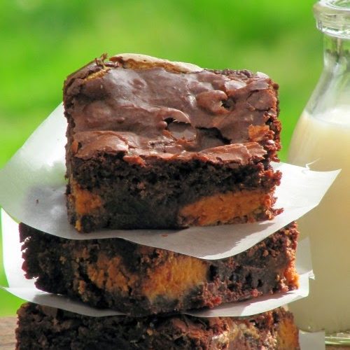 Stack of three fluffernutter brownies separaged with pieces of white parchment paper. Brownies are made with brownie mix, Reese's peanut butter eggs, marshmallows and chocolate chips