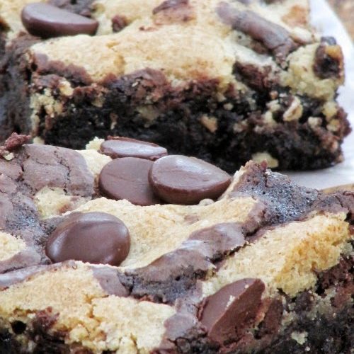 Close up image of the tops and side of two large chocolate chip cookie brownies with a layer of chocolate chip cookies on top studded with chocolate chips