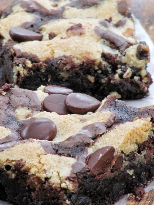 Close up image of the tops and side of two large chocolate chip cookie brownies with a layer of chocolate chip cookies on top studded with chocolate chips