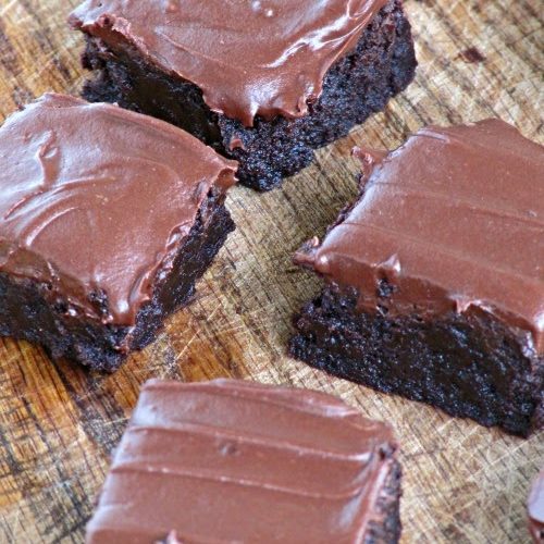 top view of several rich chocolate bourbon brownies with hershey's fudge frosting sitting on a wooden surface