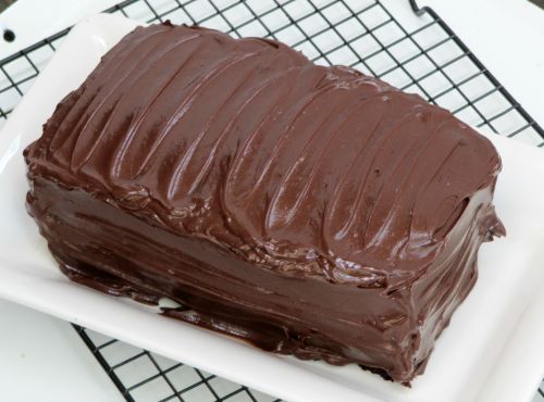 Angled view of rich chocolate Beatty's chocolate cake with chocolate buttercream icing on a white platter.