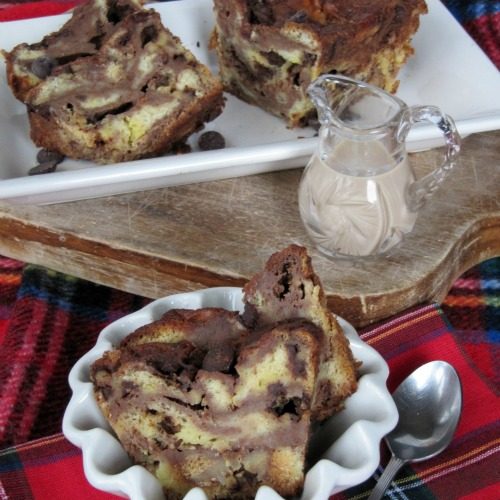 Two slices of Bailey's chocolate brioche bread pudding in a white serving dish with a small white bowl of chocolate bread pudding in the foreground