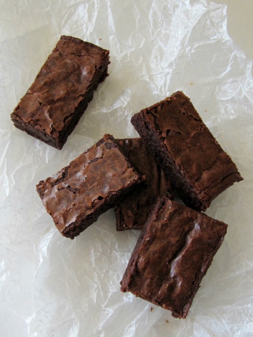 overhead view of triple chocolate brownies sliced on a piece of parchment paper.
