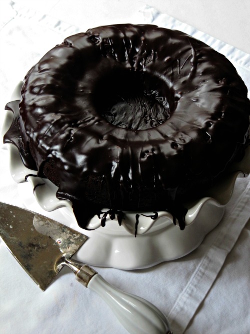 Top view of round tube pan brick street chocolate cake with chocolate drizzle frosting on a cake stand