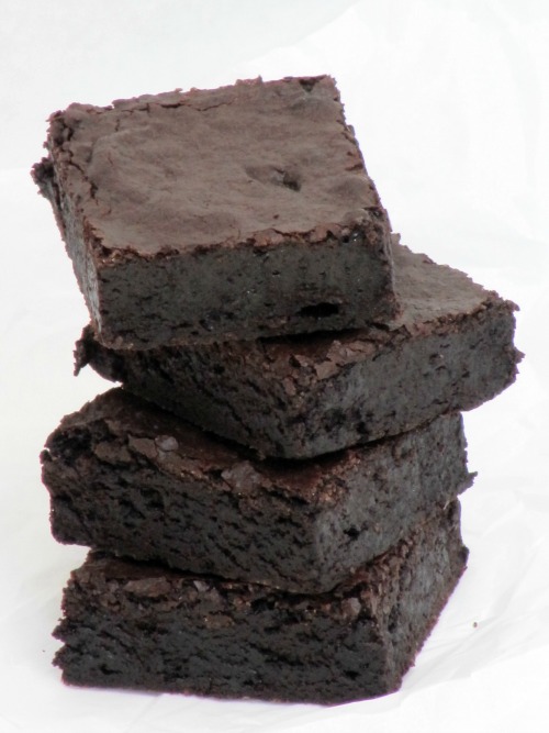 A stack of rich fudgy cocoa brownies is sitting on a white table