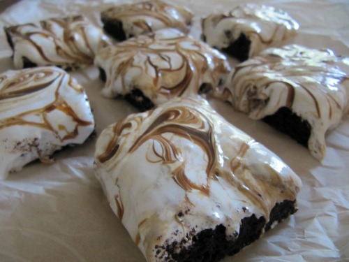 caramel and marshmallow covered dulce de leche fluff brownies scattered on a piece of parchment paper.