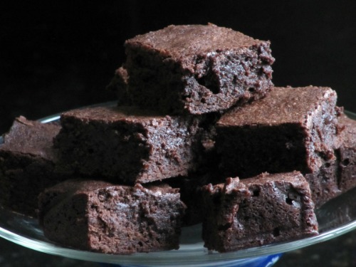 cloesup of a stack of deep chocolate classic fudge brownies cut in large squares on a platter.