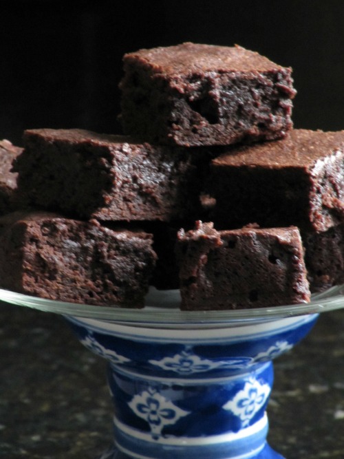 front shot of a tall blue and white footed cake stand holding a stack of thick classic fudge brownies.