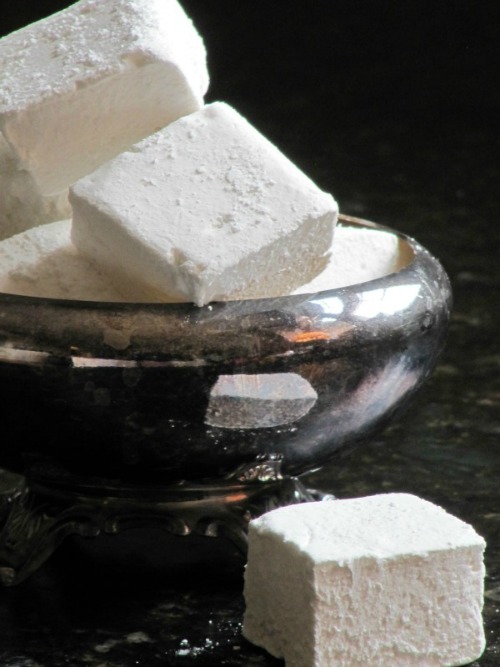 A silver dish holds several large square homemade marshmallows ready to top a cup of steaming Irish hot chocolate.