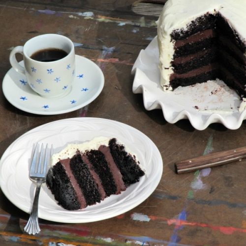 chocolate cake with fudge filling and white frosting sliced and served on a white plate.