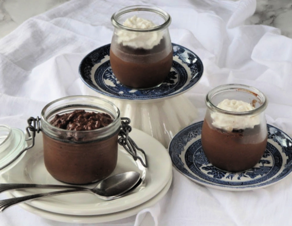 side view of jars of bailey's chocolate rice pudding on white plates with whipped cream on top.