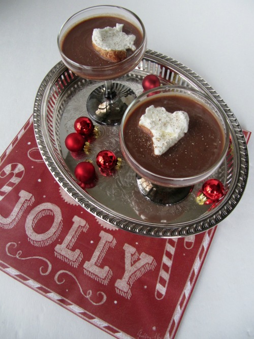overhead view of two dark chocolate and vanilla ice cream bailey's frozen hot chocolate  cocktails decorated with whipped cream that are sitting on an oval silver tray with red christmas ornaments. The tray is on a red and white christmas table mat.