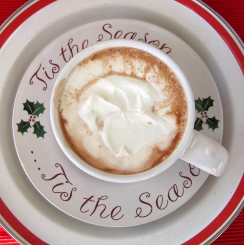 overhead view of a white Christmas platter holding a christmas plate and a white mug filled with rich hershey's perfectly hot chocolate cocoa drink topped with whipped cream.
