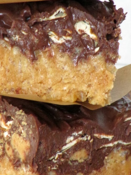 Closeup of two rich peanut butter pretzel  bars with chocolate, peanut butter, and pretzel topping on rice krispie bars.
