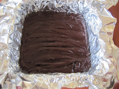An overhead view of a pan of Browned Butter Brownies from Bon Appetit shown cooling after baking in a foil-lined baking pan.