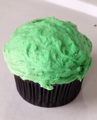 One chocolate Bailey's irish cream cupcake with light green buttercream frosting flavored with Bailey's irish cream is on a white table.