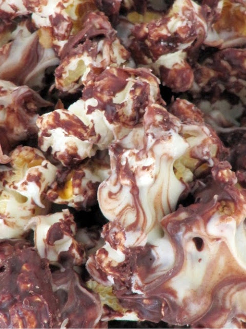 A closeup image of triple chocolate kettle corn that has white, dark and milk chocolate drizzled over it.