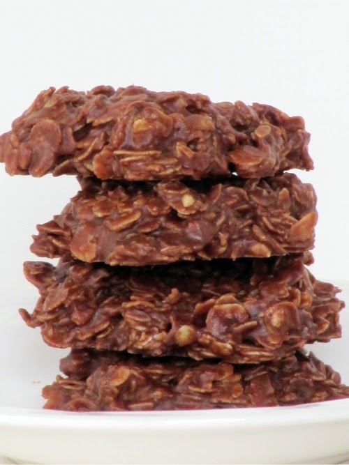 A stack of four chocolate peanut butter oatmeal no bake cookies are sitting on a white plate against a white background.