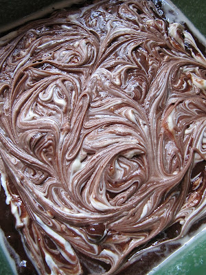 A closeup of the swirled cream cheese and brownie top of a pan of cream cheese brownies ready to be baked.