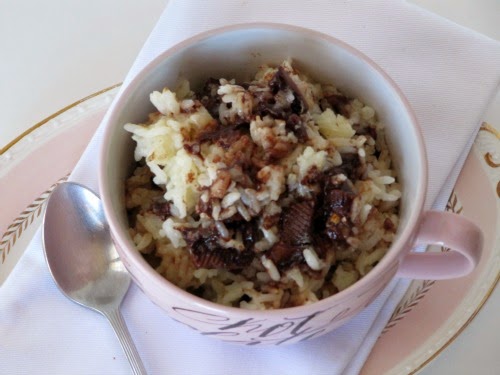 Overhead veiw of a pink cup holding chocolate almond toffee rice pudding that is made with rice, sugar, milk, cream and a chocolate toffee candy bar.