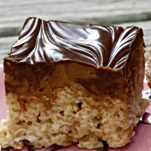 One large double peanut butter chocolate rice krispie square with a rice cereal base and a thick layer of melted chocolate chips swirled with reese's peanut butter bunny candies on a beige surface with swirls of chocolate against a light gray background.