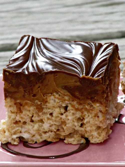 One large double peanut butter chocolate rice krispie square with a rice cereal base and a thick layer of melted chocolate chips swirled with reese's peanut butter bunny candies on a beige surface with swirls of chocolate against a light gray background.