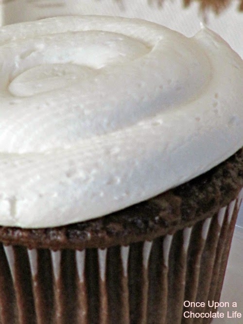 A super closeup shot of white creamy marshmallow buttercream  for chocolate cupcakes on a chocolate cupcake.