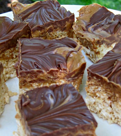 Several large double peanut butter chocolate rice krispie treat squares with smooth chocolate and peanut butter swirls are on a white plate.