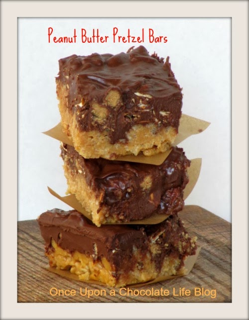 A stack of three Peanut butter pretzel bars made with rice krispies and Reese's peanut butter pumpkins are separated with light brown parchment paper squares on a wood surface.