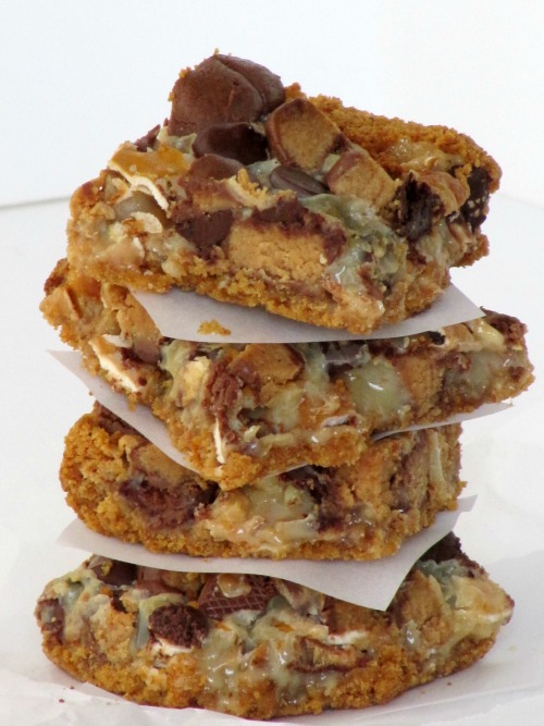 A stack of four pretzel peanut butter cup magic bars sits on a white surface against a white background.