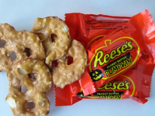 A pile of Reese's round peanut butter pumpkins are sitting next to the famous orange Reese's packaged pumpkins ready to make peanut butter pretzel bars.