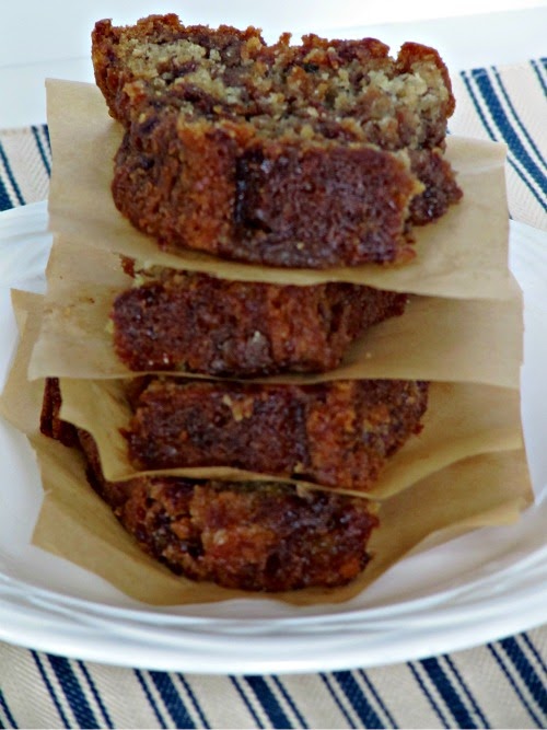A closeup photo of several stacked slices of Reese's Peanut Butter Egg Banana Bread separated by pieces of light brown parchment paper on a white plate.