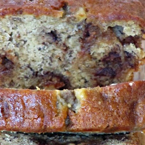 Closeup image of a sliced loaf of Reese's Peanut Butter Egg Banana Bread that shows the Reese's candy within the bread slices and the golden brown tops of the slices.