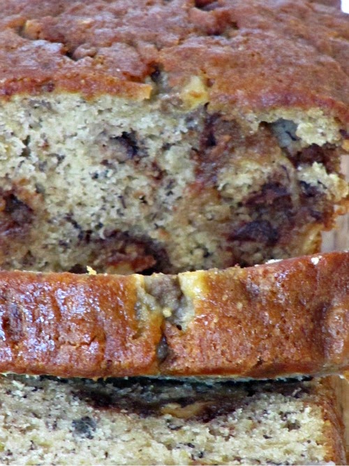 Closeup image of a sliced loaf of Reese's Peanut Butter Egg Banana Bread that shows the Reese's candy within the bread slices and the golden brown tops of the slices.