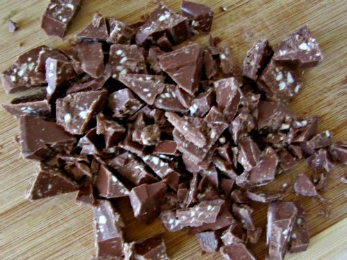 A pile of Toblerone chocolate candy chopped into chunks to make Toblerone cereal treats are sitting on a wood table.