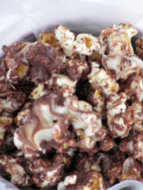 A closeup image of triple chocolate kettle corn with drizzles of white, semi-sweet and milk chocolate chips.